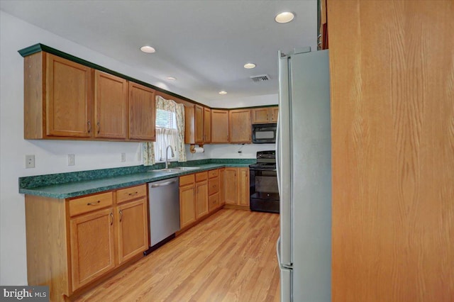 kitchen featuring sink, black appliances, and light hardwood / wood-style floors