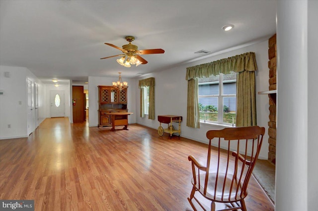 living area featuring ceiling fan with notable chandelier and light wood-type flooring