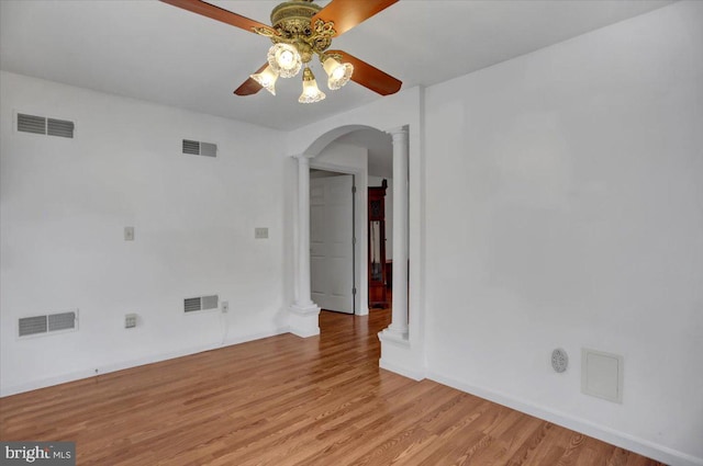 empty room with light wood-type flooring, ornate columns, and ceiling fan