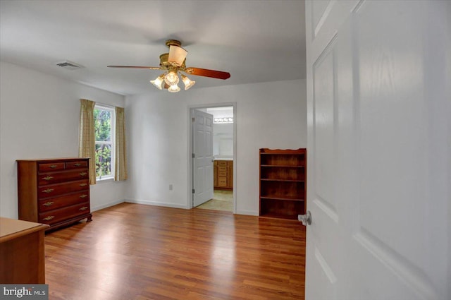 unfurnished bedroom featuring connected bathroom, ceiling fan, and hardwood / wood-style flooring