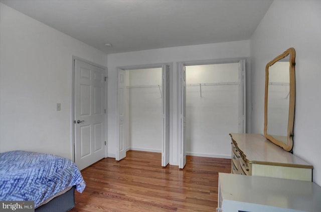 bedroom featuring hardwood / wood-style flooring and two closets