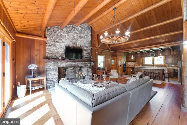 living room with beam ceiling, wood walls, wood ceiling, and light wood-type flooring