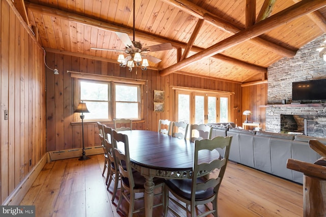 dining room with a baseboard heating unit, vaulted ceiling with beams, light hardwood / wood-style flooring, and a healthy amount of sunlight