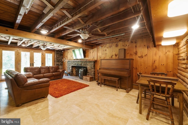 living room with a stone fireplace, ceiling fan, wooden walls, and wood ceiling