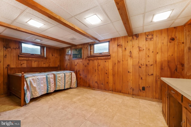 bedroom featuring a paneled ceiling and wooden walls