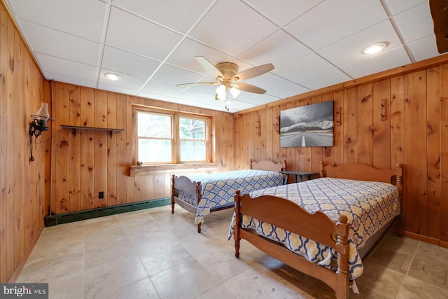 bedroom with ceiling fan, wooden walls, and a baseboard radiator