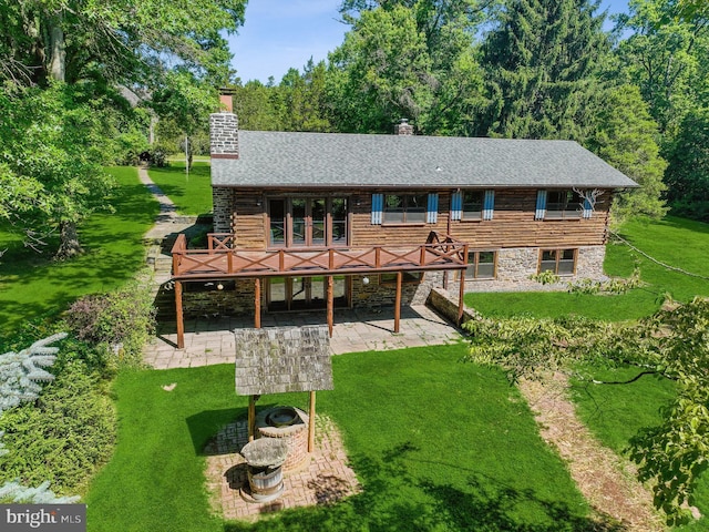 rear view of house with a deck, a patio area, and a lawn