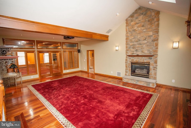 living room featuring french doors, hardwood / wood-style flooring, a stone fireplace, and lofted ceiling