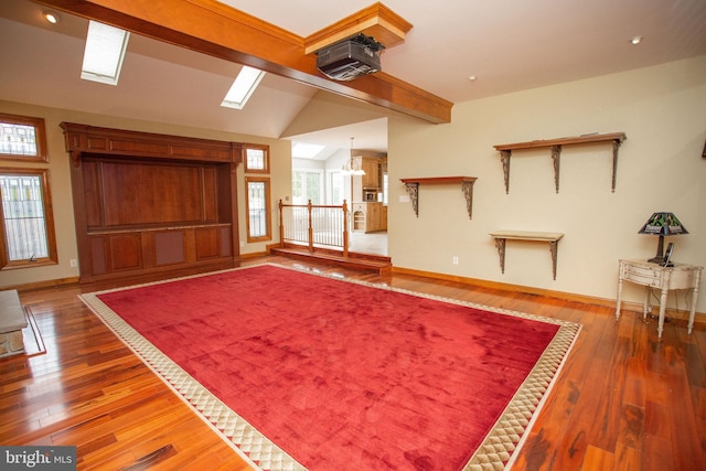 unfurnished living room with an inviting chandelier, lofted ceiling with beams, and hardwood / wood-style flooring