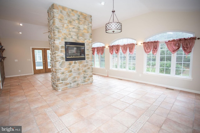 unfurnished living room featuring light tile patterned floors, vaulted ceiling, and a stone fireplace