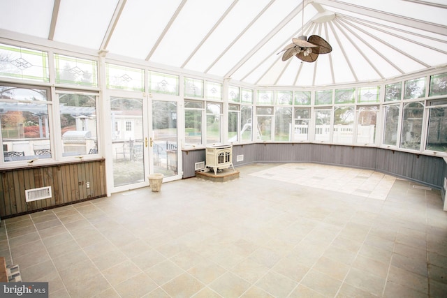 unfurnished sunroom featuring a wood stove, ceiling fan, and vaulted ceiling