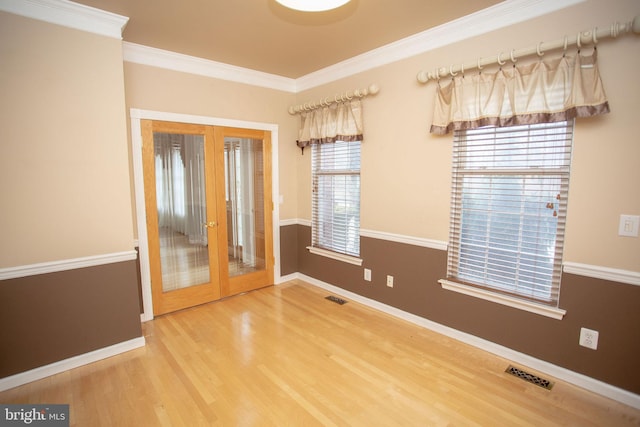 spare room with a healthy amount of sunlight, crown molding, french doors, and wood-type flooring