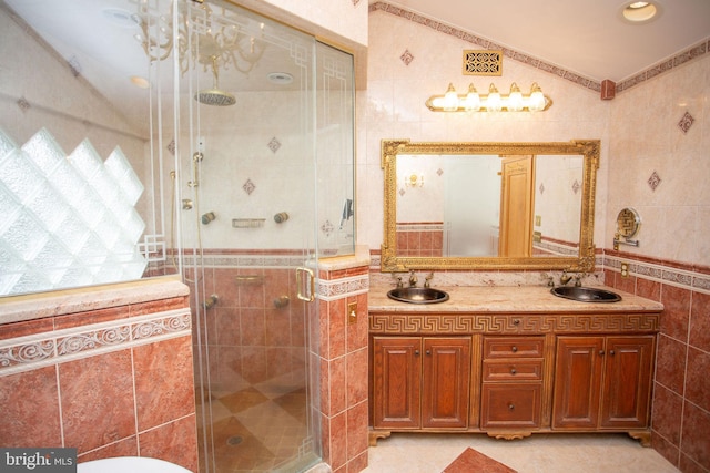 bathroom featuring a shower with door, vanity, tile walls, and tile patterned flooring