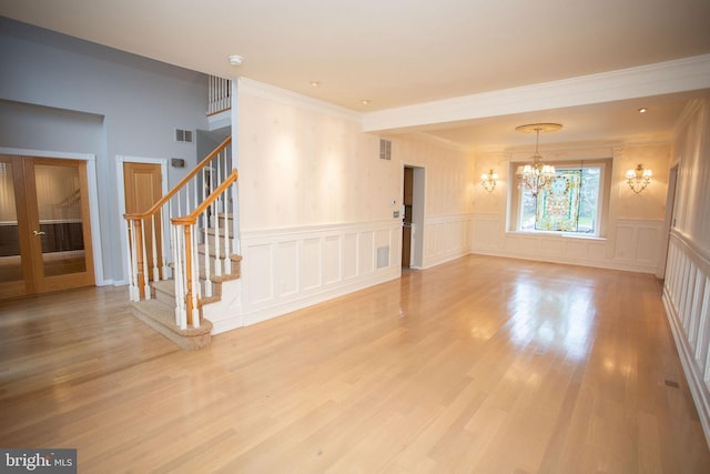 spare room featuring hardwood / wood-style floors, an inviting chandelier, and ornamental molding