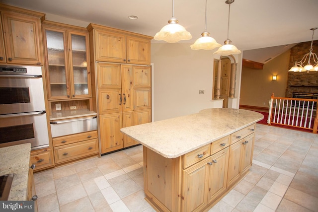 kitchen featuring light stone countertops, pendant lighting, stainless steel double oven, and a center island