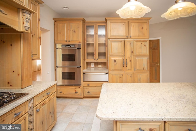 kitchen with light stone countertops, gas cooktop, double oven, pendant lighting, and light tile patterned flooring