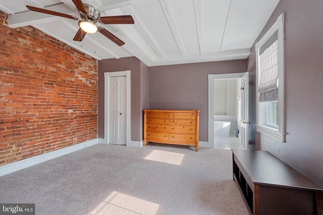 unfurnished bedroom featuring connected bathroom, ceiling fan, light colored carpet, and brick wall