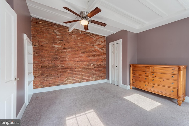 unfurnished bedroom with carpet, lofted ceiling with beams, ceiling fan, brick wall, and a closet