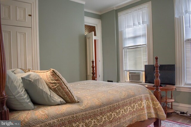 bedroom featuring multiple windows, crown molding, hardwood / wood-style floors, and cooling unit