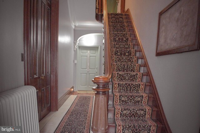 stairway featuring tile patterned floors, crown molding, and radiator heating unit