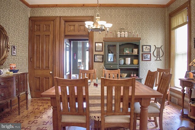 dining space with crown molding and a notable chandelier