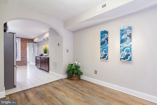 hall featuring brick wall and light hardwood / wood-style flooring