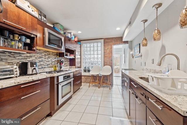 kitchen featuring light stone countertops, decorative backsplash, sink, and stainless steel appliances