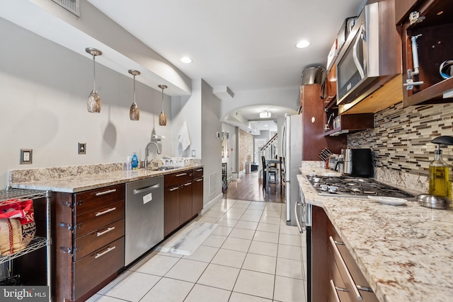 kitchen with pendant lighting, backsplash, sink, light tile patterned floors, and appliances with stainless steel finishes