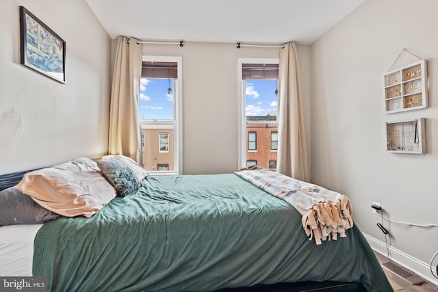 bedroom with multiple windows and hardwood / wood-style flooring