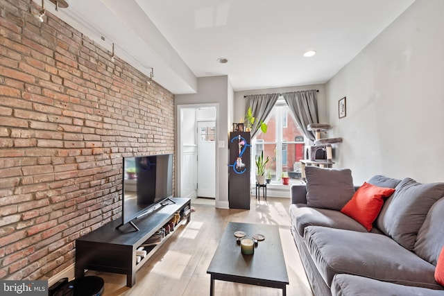 living area featuring recessed lighting, baseboards, brick wall, and wood finished floors