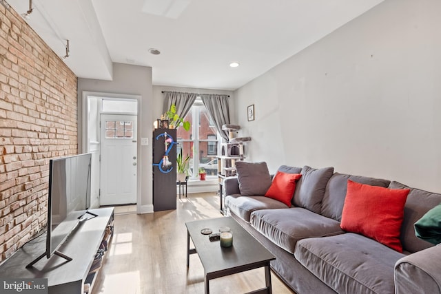 living room with light hardwood / wood-style floors and brick wall