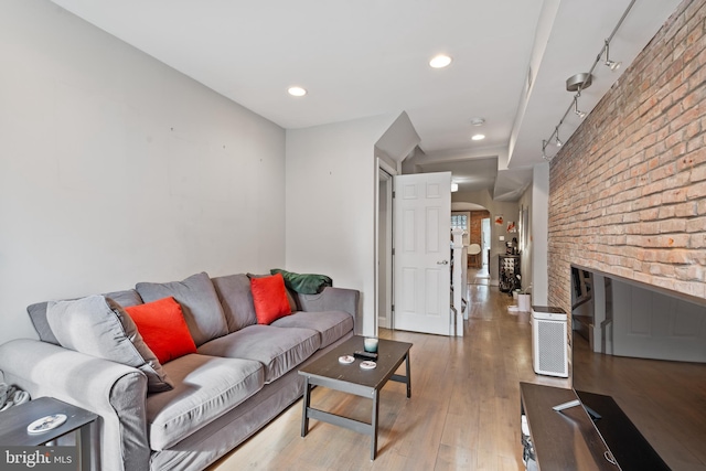 living room with a fireplace, hardwood / wood-style floors, and brick wall