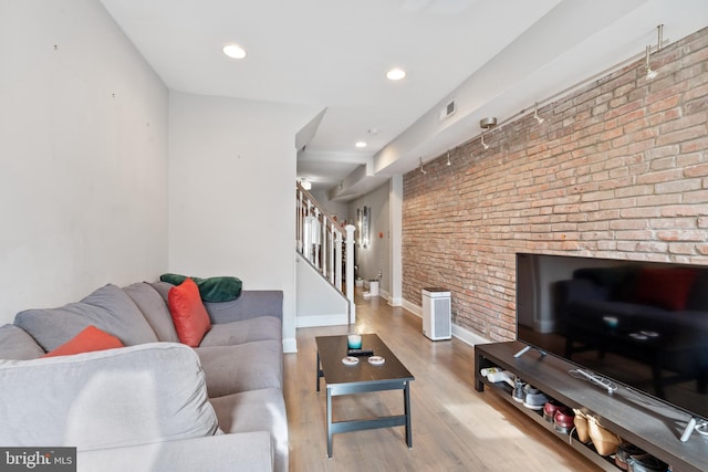 living room featuring brick wall and light hardwood / wood-style flooring