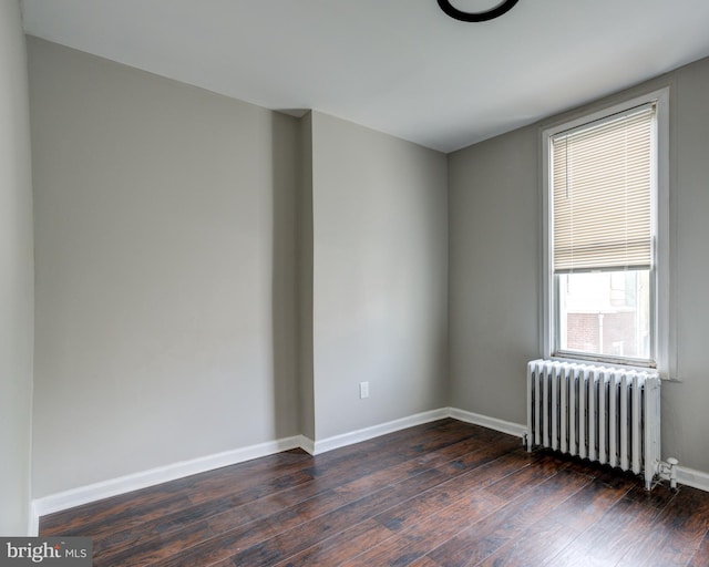 spare room with dark wood-type flooring and radiator heating unit