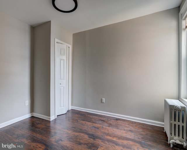 unfurnished bedroom featuring dark hardwood / wood-style floors and radiator