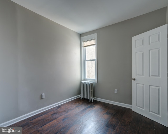 empty room featuring radiator heating unit and dark hardwood / wood-style flooring