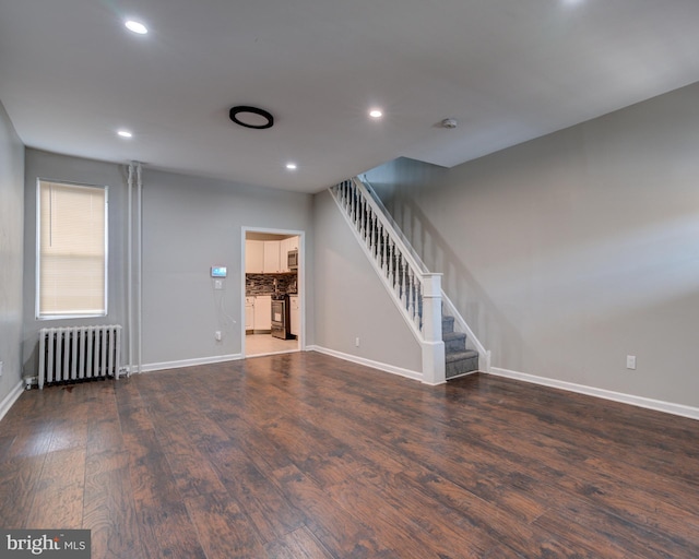 unfurnished living room with radiator heating unit and dark wood-type flooring