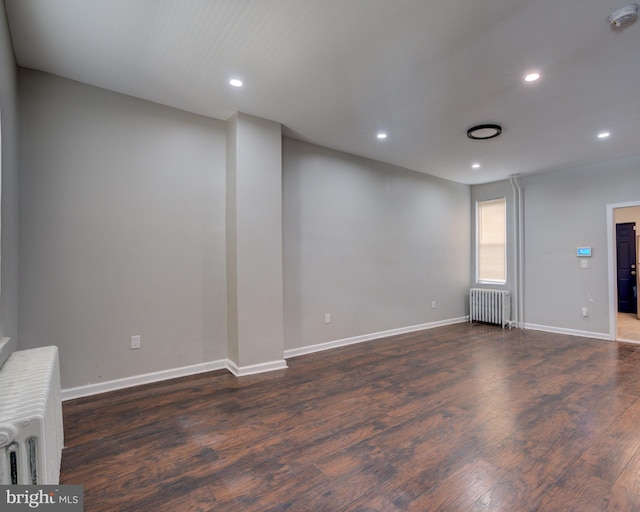 unfurnished living room with radiator heating unit and dark hardwood / wood-style floors