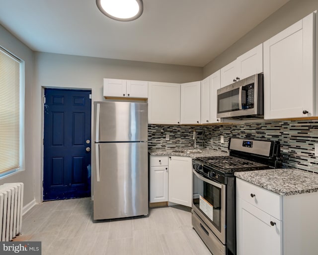 kitchen featuring white cabinetry, appliances with stainless steel finishes, and radiator heating unit