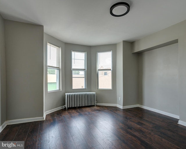 unfurnished room with radiator and dark hardwood / wood-style flooring