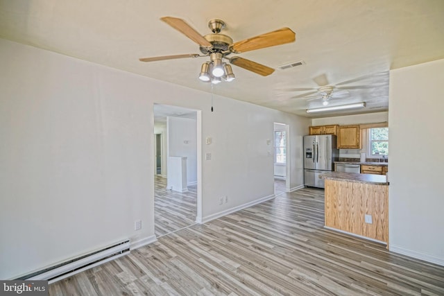 kitchen with a baseboard radiator, stainless steel appliances, sink, ceiling fan, and light hardwood / wood-style flooring