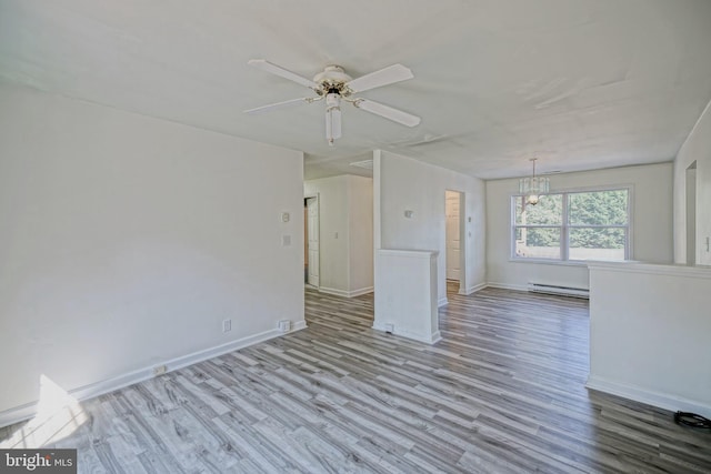 unfurnished living room with ceiling fan with notable chandelier, baseboard heating, and light hardwood / wood-style flooring