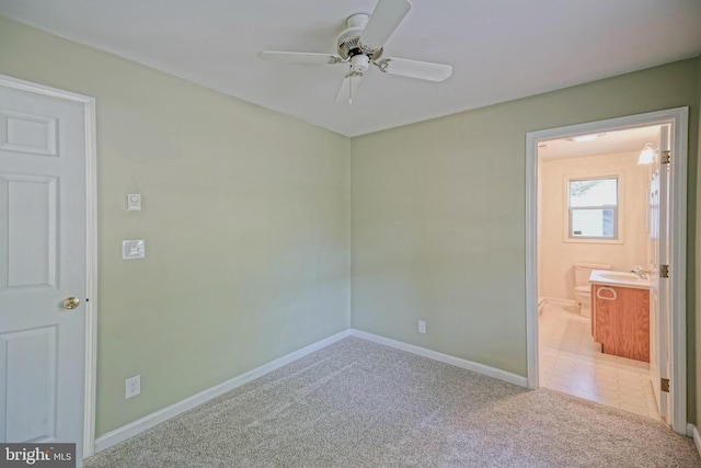 unfurnished bedroom with ensuite bathroom, ceiling fan, sink, and carpet flooring