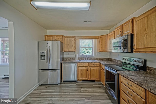 kitchen featuring appliances with stainless steel finishes, a healthy amount of sunlight, a baseboard radiator, and sink