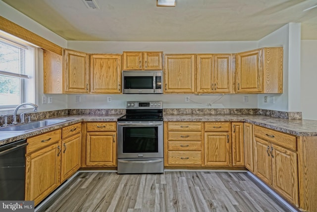 kitchen featuring appliances with stainless steel finishes, light hardwood / wood-style flooring, and sink