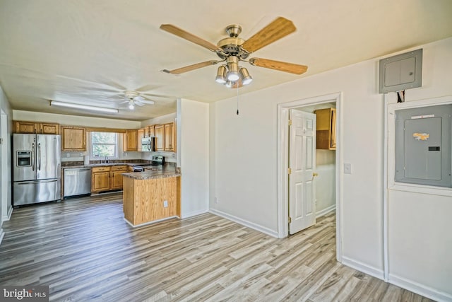 kitchen featuring ceiling fan, appliances with stainless steel finishes, electric panel, light hardwood / wood-style flooring, and sink