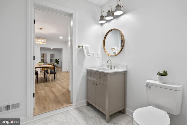 bathroom with vanity, a notable chandelier, toilet, and hardwood / wood-style floors