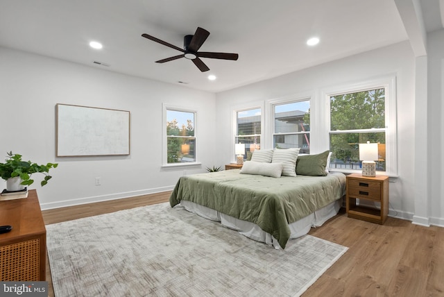 bedroom featuring multiple windows, ceiling fan, and light wood-type flooring