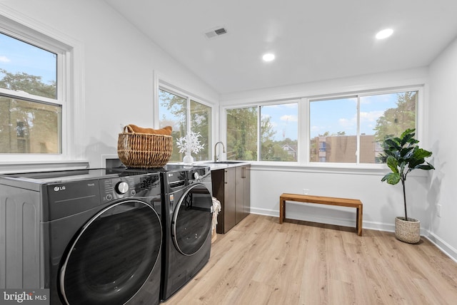 laundry room with light hardwood / wood-style floors, sink, cabinets, and washing machine and clothes dryer