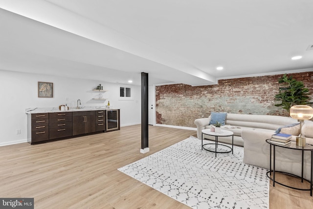 living room with sink, brick wall, light wood-type flooring, and wine cooler